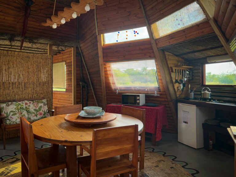 A cozy wooden cabin interior featuring a dining area, kitchenette, and rustic decor.
