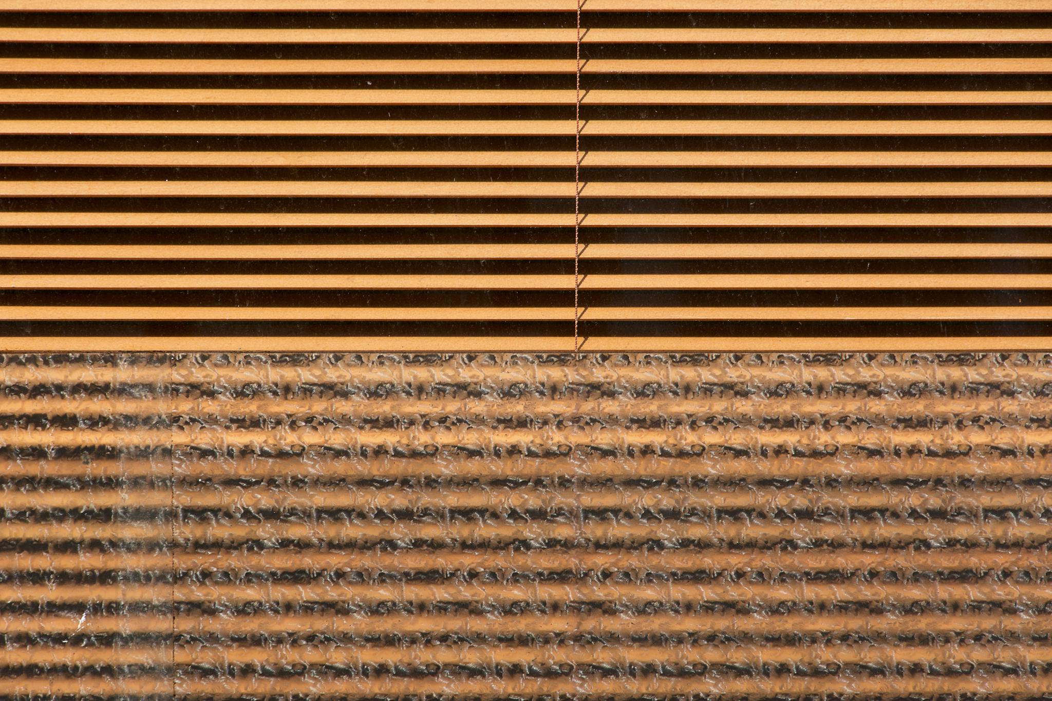 Close-up view of brown blinds with intricate pattern texture of foil and fabric.