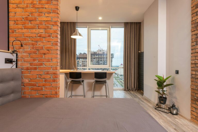 Contemporary apartment interior featuring brick walls and a view of the cityscape through large windows.